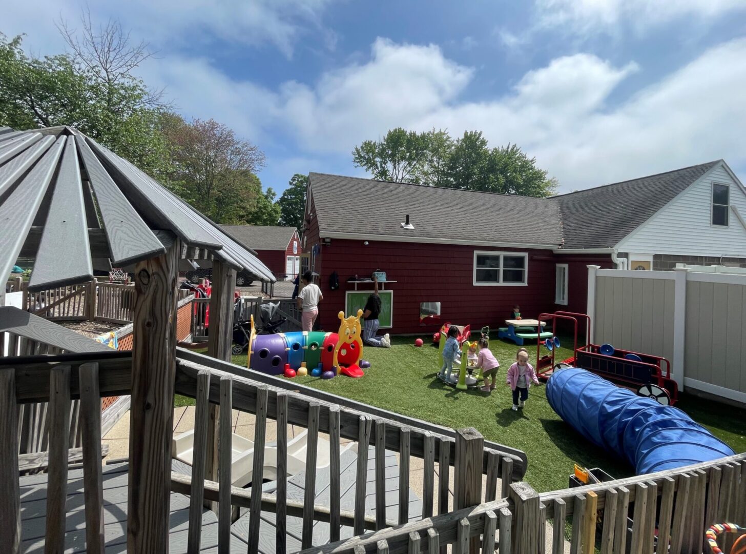 Children playing in a backyard with toys and a red barn-like building.